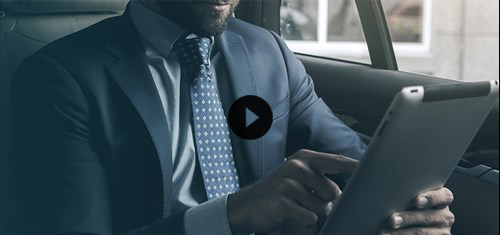 Uomo in abito elegante opera in mobilità tramite il proprio tablet a cui è sovrapposta un icona player video.