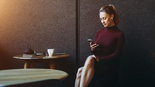 Giovane donna paga in un caffè con il proprio smartphone.