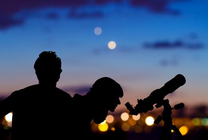 Coppia guarda il cielo con un cannocchiale.